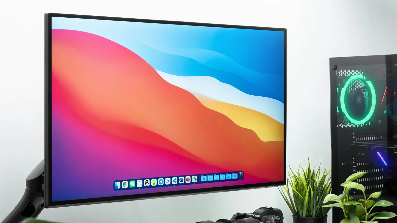 High-resolution monitor on a desk running macOS beside a gaming PC